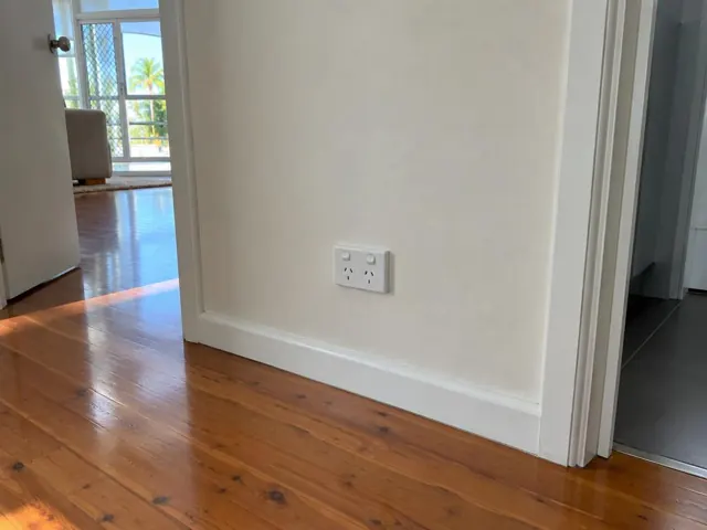 New white power point on a painted wall beside timber flooring and doorways in Hope Island